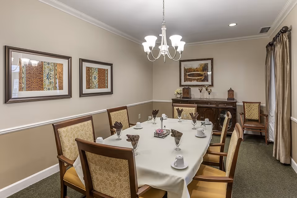 Formal dining room with a table set for six, upholstered chairs, a chandelier, framed artwork, and a sideboard.