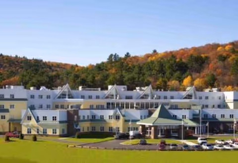 Front exterior of Merrimack County Nursing Home with parking lot and autumn trees.