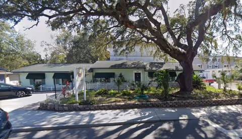 Front view of Wild Flower Inn, a single-story senior living facility with trees.