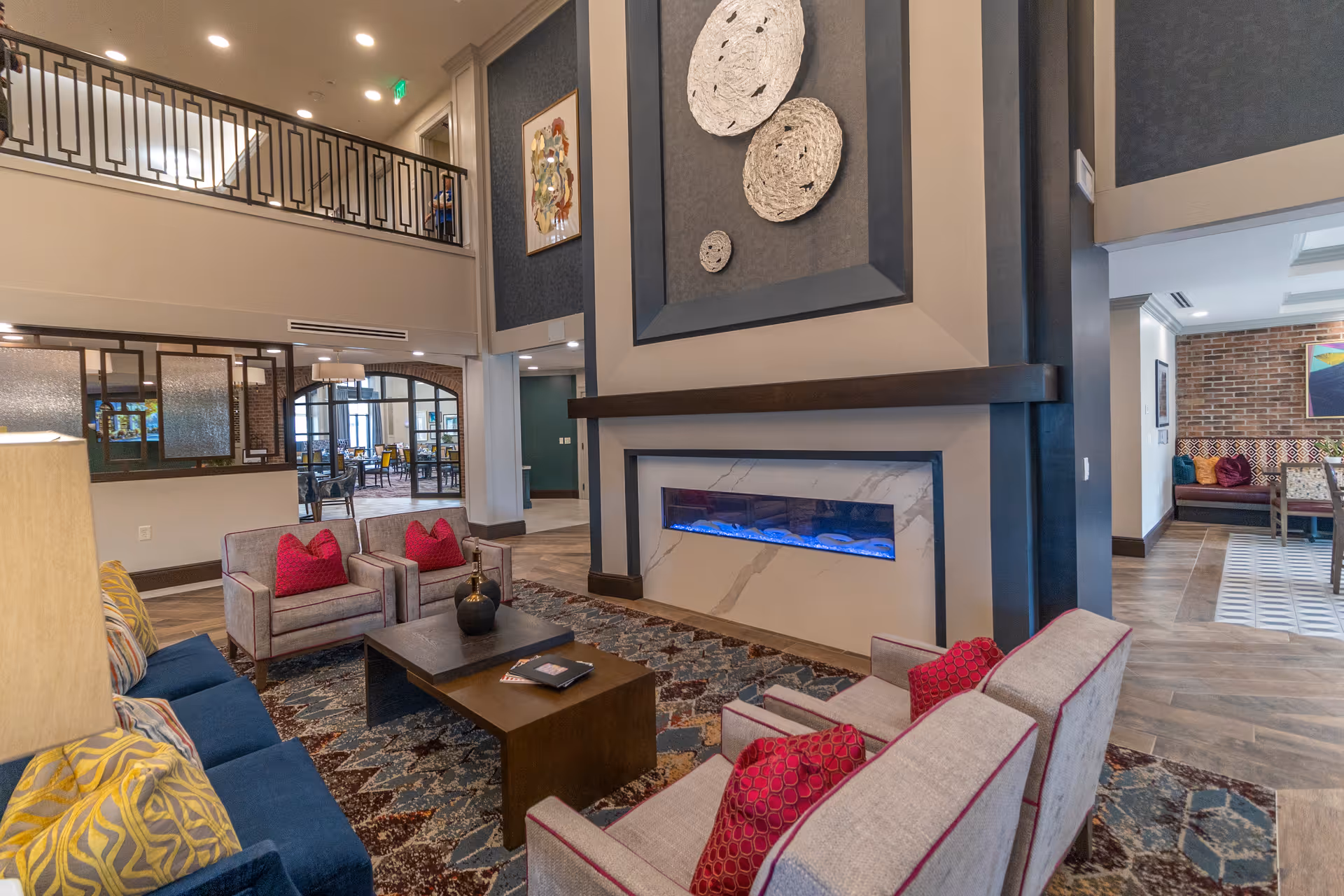 Lounge area with sofas and armchairs arranged around a coffee table and a modern linear fireplace beneath large decorative wall art.