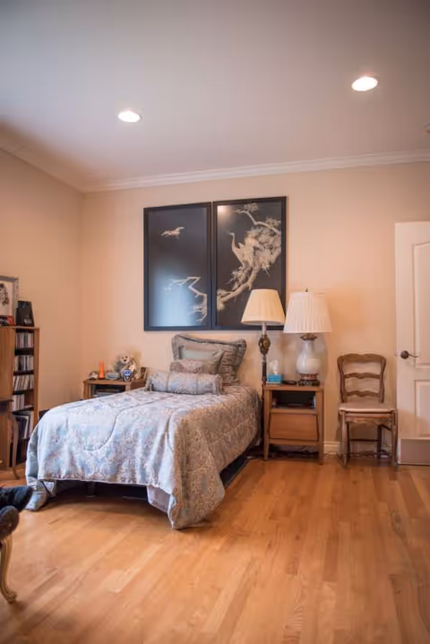 A neatly made bed with blue patterned cover in a cozy bedroom.