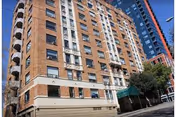 A tall brick senior living building with balconies and a street level entrance.