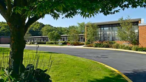 Exterior view of Atria Huntington senior living facility with curved driveway and trees.