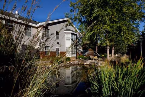 Woodbury Health Care Center exterior with a pond, trees, and landscaped grasses.