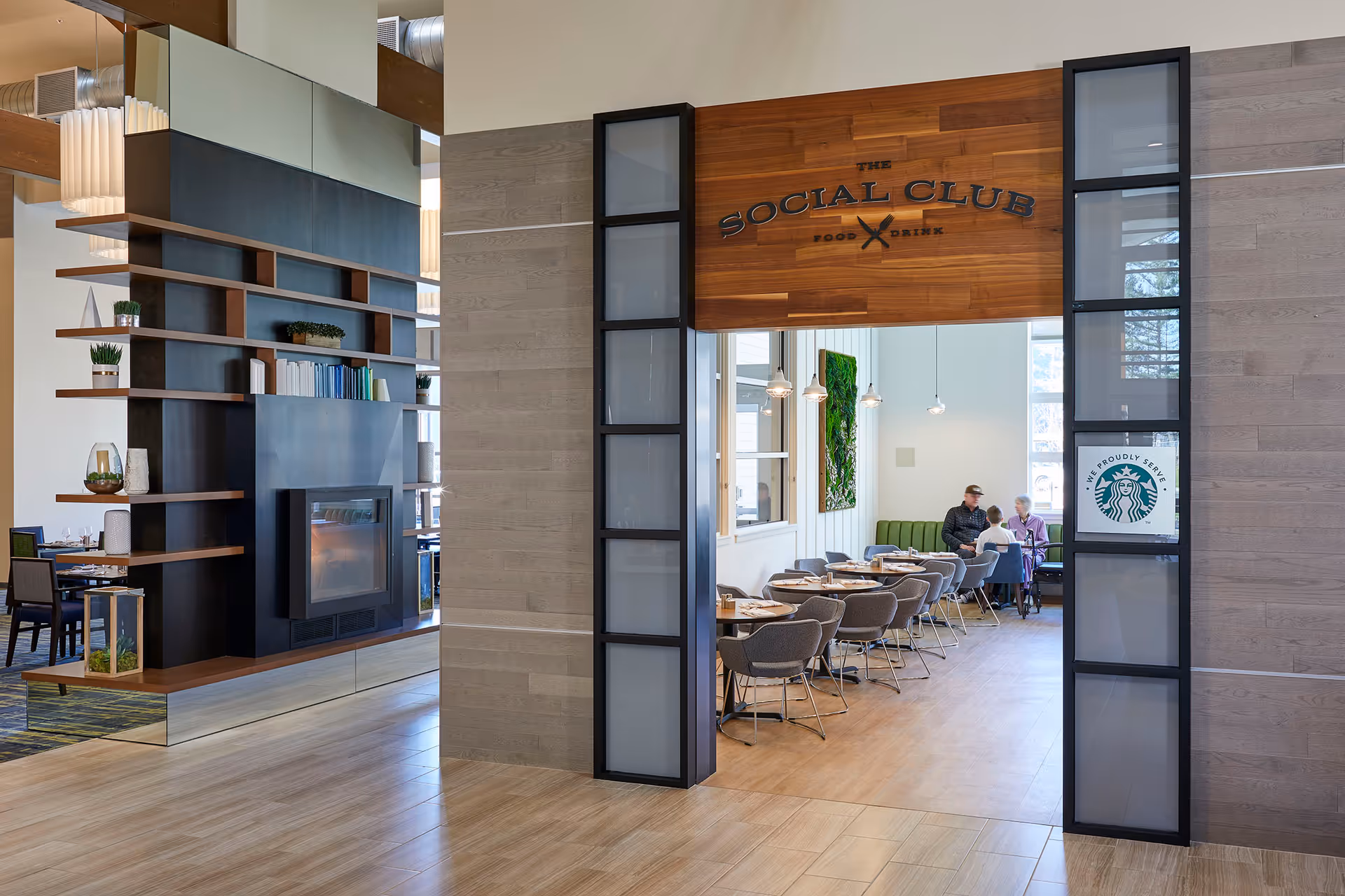 Entrance to 'The Social Club' dining area with tables, chairs, and a few residents seated inside.