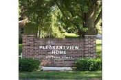 Brick entrance sign reading "PLEASANTVIEW HOME" set on a lawn with trees behind it.