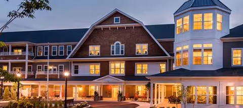 Exterior view of Laurelwood at the Pinehills, lit at dusk.