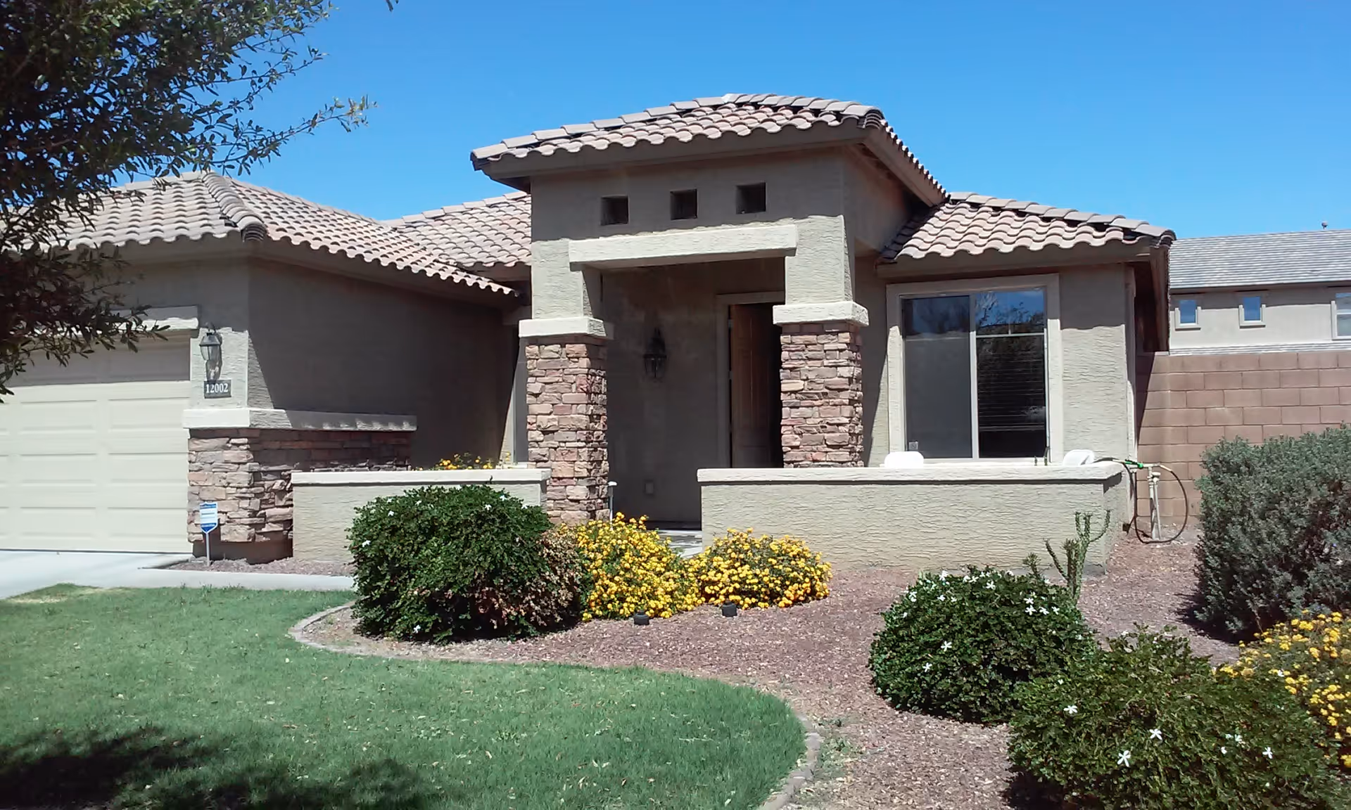 Front exterior of a single-story senior living home with stone accents and landscaped yard