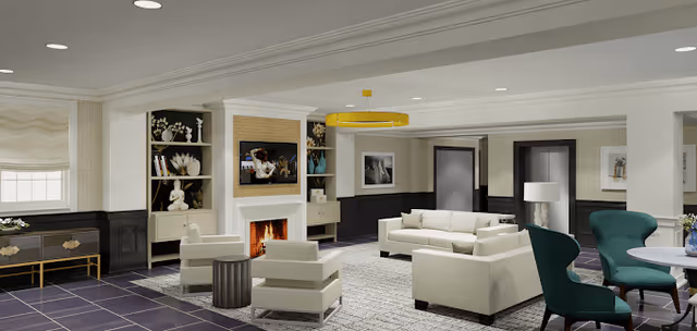 A spacious and elegant living room area with modern white sofas and armchairs arranged around a fireplace. The room features built-in shelves with decorative items, a large window with a beige Roman shade, a yellow circular ceiling light fixture, and a mix of dark and light wall paneling. There are also teal armchairs and a small round table on the right side.