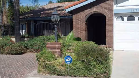 Front exterior of Genesis Manor IV with brick archway entry and surrounding shrubs.