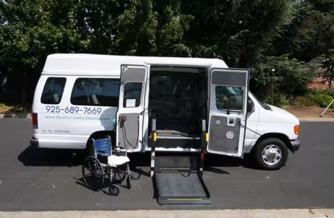 White van with deployed wheelchair ramp and a wheelchair outside Qcare Residential Facility