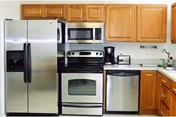 Kitchen with stainless steel refrigerator, oven, microwave, dishwasher, oak cabinets, and small countertop appliances on the counter.