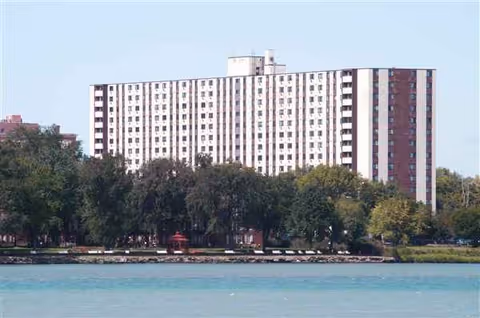 River Towers: a tall white residential building by water with trees nearby.