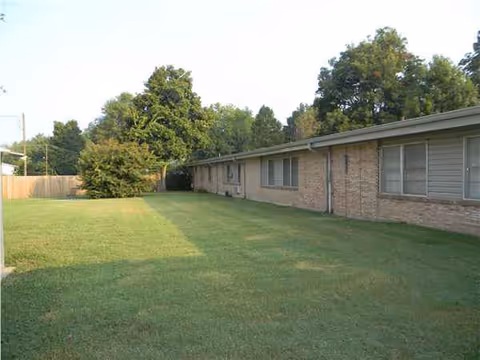 Charleston Manor exterior: a single-story brick building beside a grassy lawn and trees.