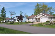 Row of single-story residential buildings with driveways and green lawns along a quiet street.