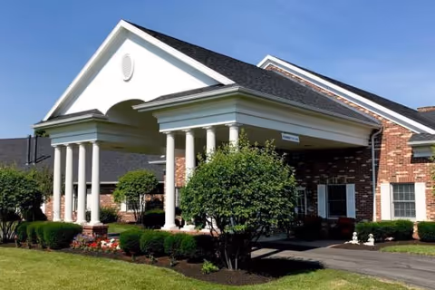 Heritage Estates entrance with brick exterior, white columns, and manicured landscaping.