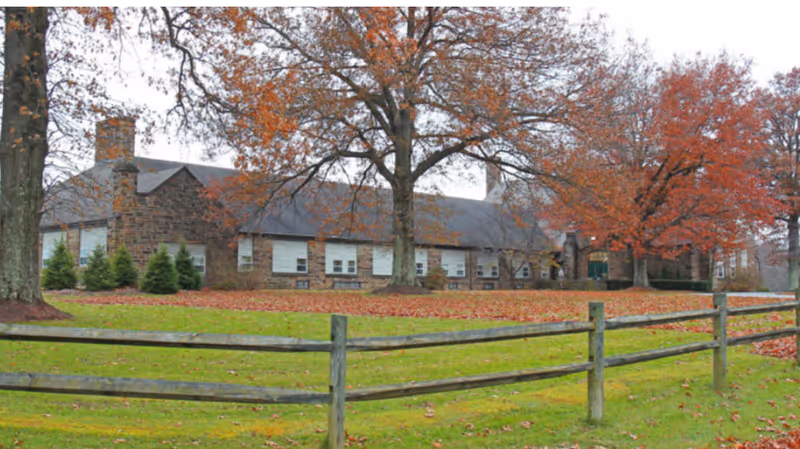 Exterior view of Greystone Country Estates featuring trees and autumn foliage.