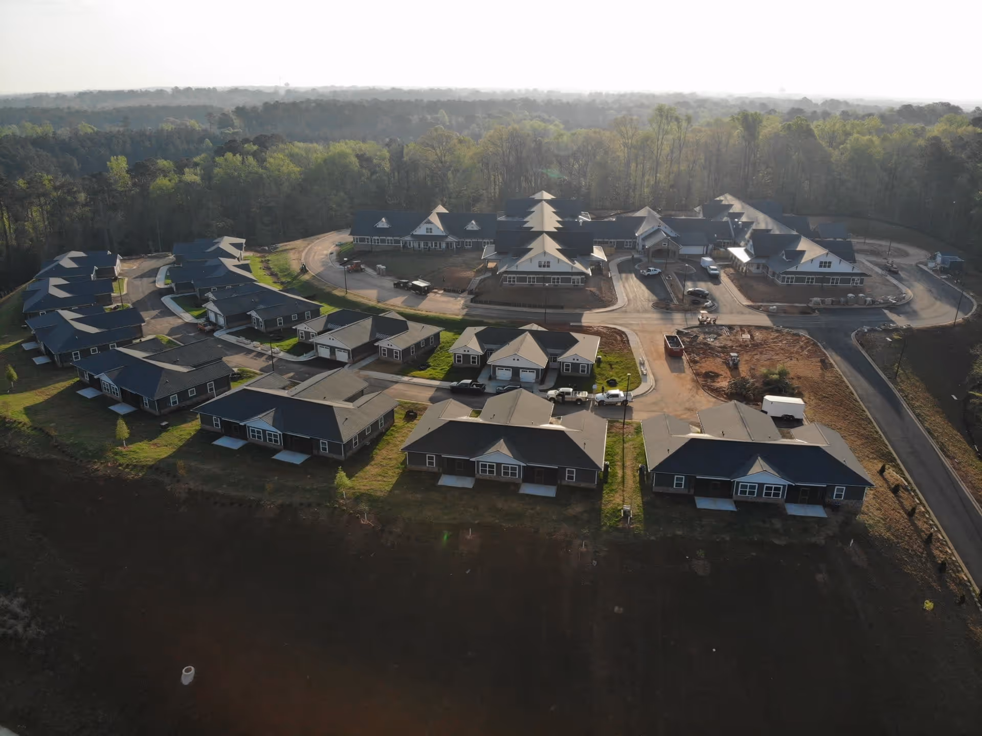 Aerial view of LaGrange Heritage Senior Living facility showing multiple single-story buildings with dark roofs arranged along curved roads, surrounded by green trees and open land.