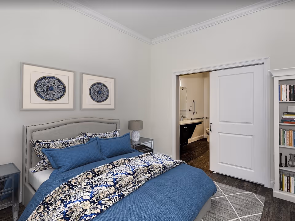 Bedroom with a blue patterned bed, nightstands, a bookshelf, and an open sliding door leading to a bathroom.