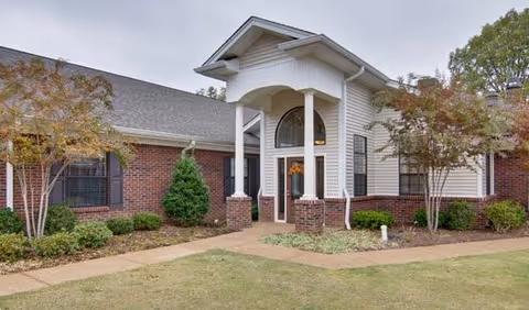 Exterior view of Olive Grove Terrace Senior Living entrance with brick and landscaping.