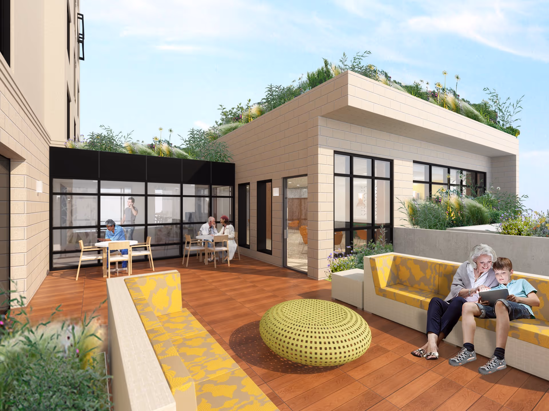 Rooftop patio with modern seating and planters where seniors and a child relax and others sit at tables beside a glass-walled building.