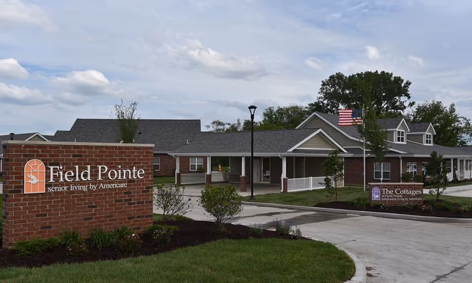 Front exterior of Field Pointe assisted living facility showing a brick entrance sign, covered entryway, and driveway.