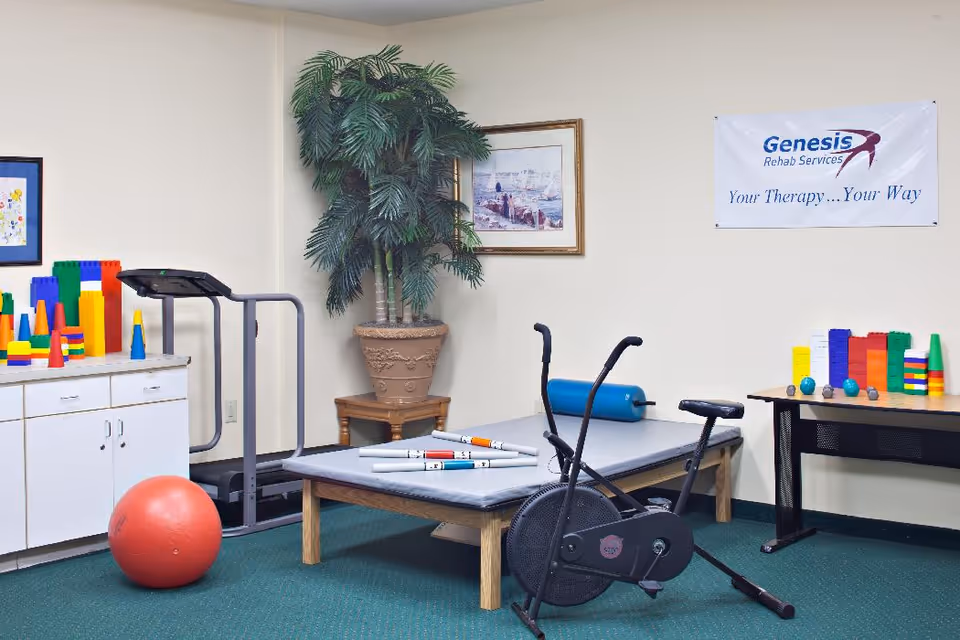 Rehabilitation therapy room with an exercise bike, treatment table, treadmill, therapy ball and colorful therapy props.