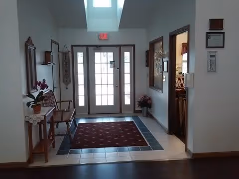 Bright interior entry foyer with glass double doors, a skylight, bench, rug, and adjacent rooms.