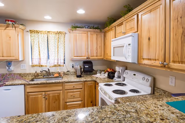 A modern kitchen with wooden cabinets, granite countertops, and kitchen appliances.