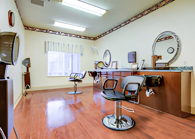 Hair-salon style interior with styling chairs, circular mirrors, and hooded hair dryers on a polished wood floor.