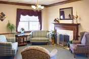 Cozy living room in a senior facility with plaid chairs and a fireplace.