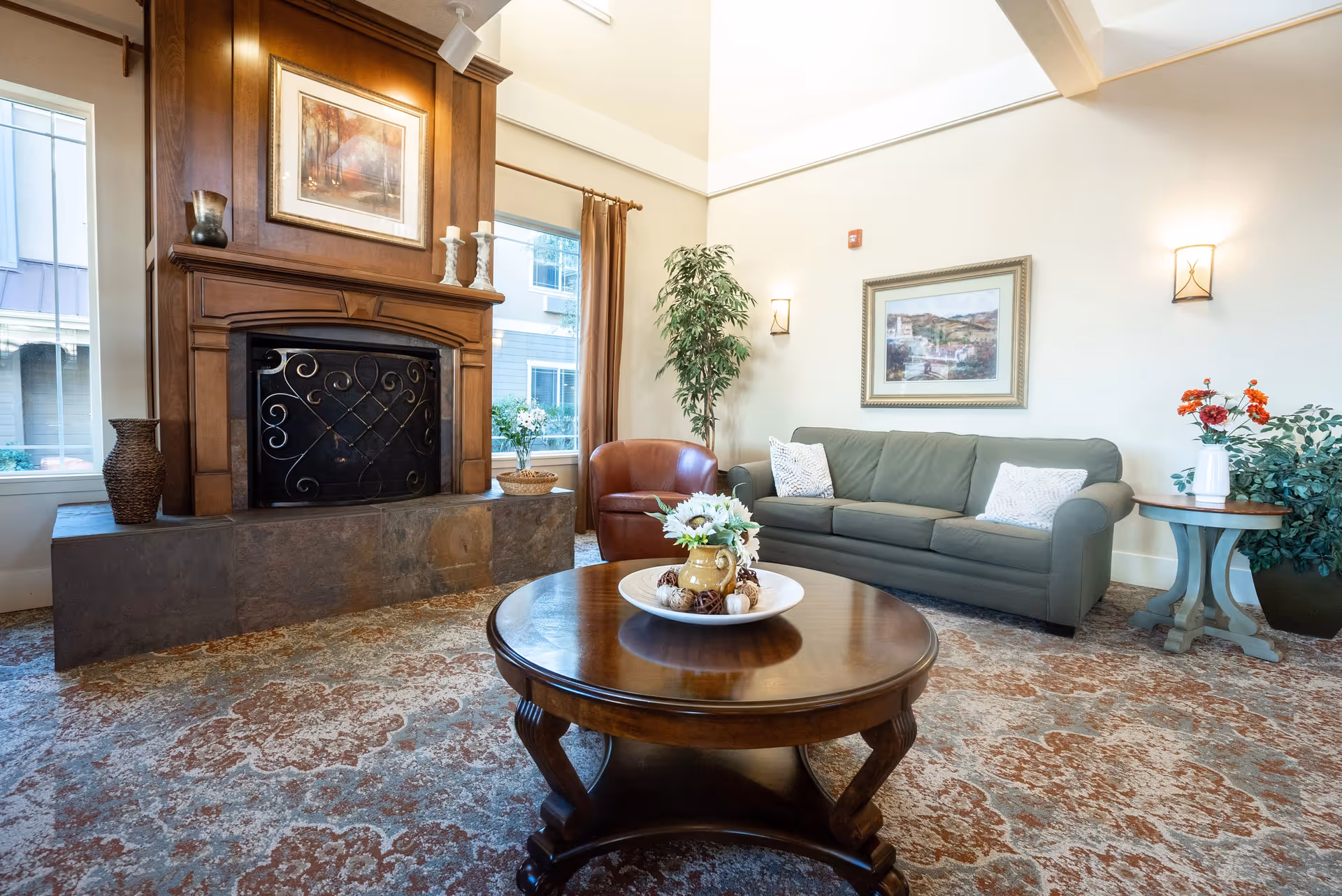 Cozy lounge area featuring a fireplace, round wooden coffee table with a centerpiece, green sofa, and an armchair.
