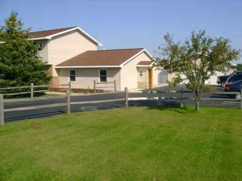 Front exterior of Culver Meadows Adult Foster Care with a green lawn and trees.