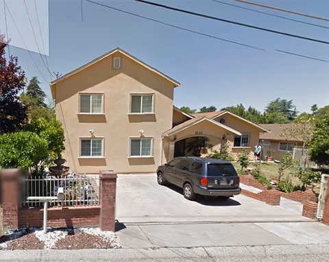 Front view of Fair Oaks Care Home with driveway, parked car, and landscaped entry.
