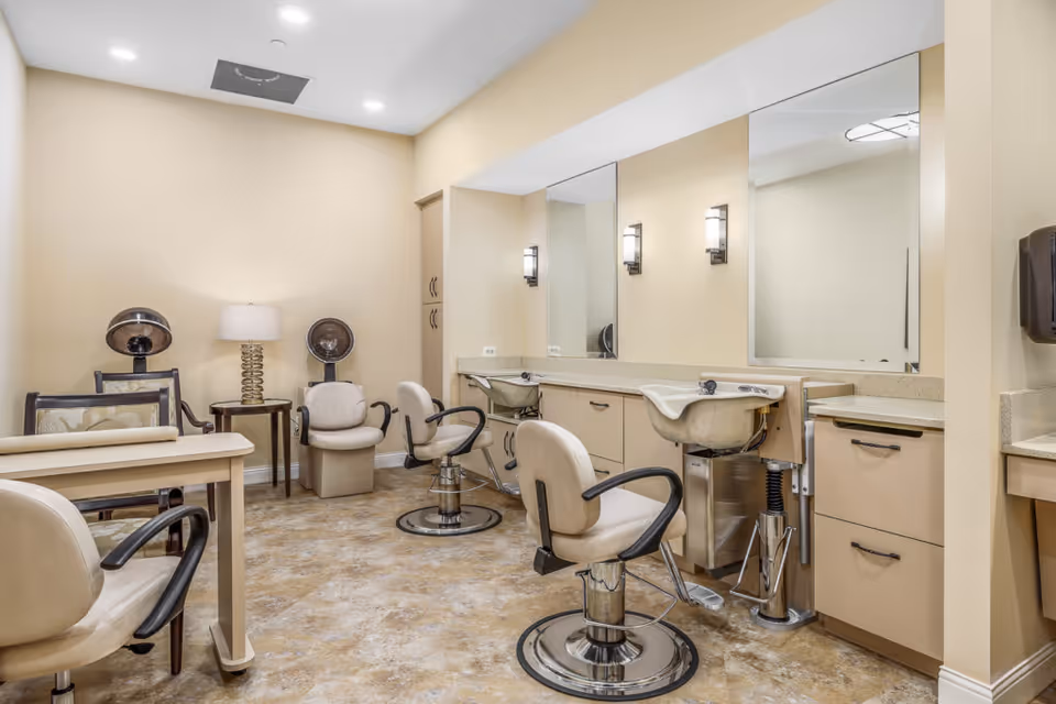 Salon room with styling chairs, shampoo sinks, mirrors and hairdryers.