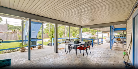 Covered patio with tiled floor, a dining table and chairs, and open views to a grassy backyard.