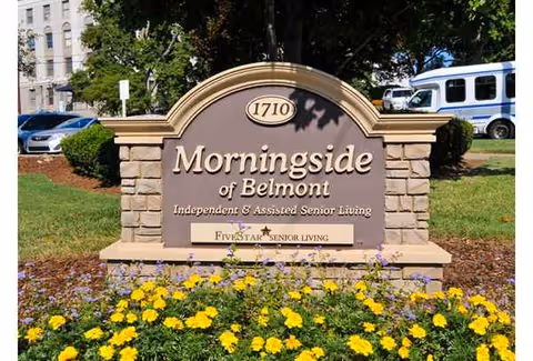 Morningside of Belmont sign on a stone pedestal with yellow flowers and greenery.