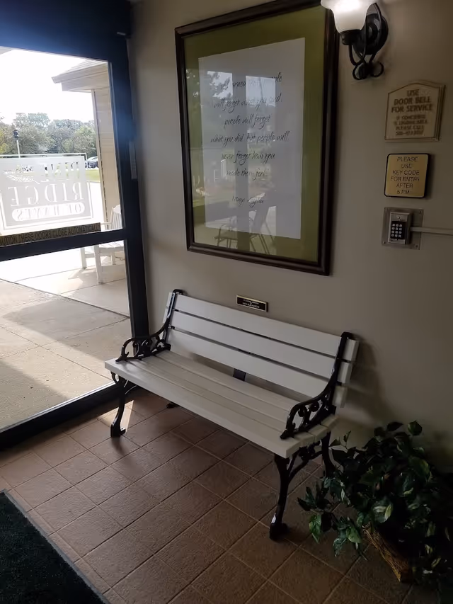 Small entry vestibule with a white bench, framed picture, access keypad, potted plant, and a glass exterior door.