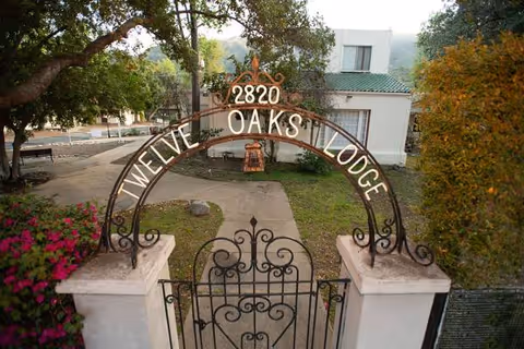 Ornate wrought-iron arch gate reading Twelve Oaks Lodge over a walkway to a building