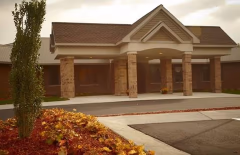 Exterior view of Medilodge of Capital Area entrance with brick columns and driveway.