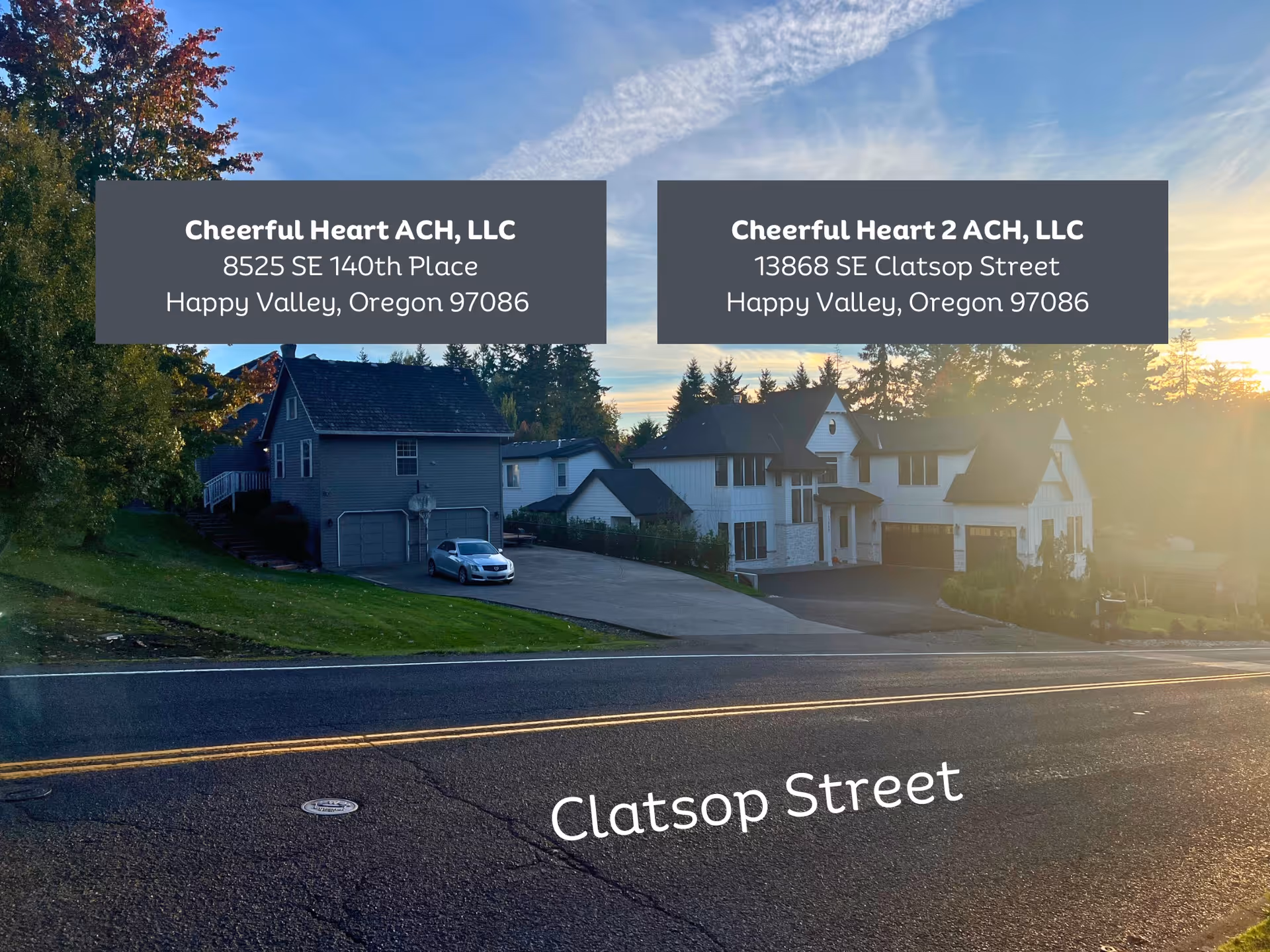 Two residential buildings at sunset with addresses displayed: Cheerful Heart ACH, LLC at 8525 SE 140th Place and Cheerful Heart 2 ACH, LLC at 13868 SE Clatsop Street, both in Happy Valley, Oregon. The street name Clatsop Street is visible on the road in front.