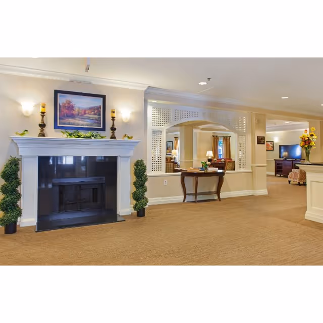 Spacious common area with a fireplace, console table, decorative plants and seating visible through an open partition.