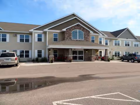 Exterior view of Vista Prairie at Copperleaf senior living facility with entrance and parked cars.