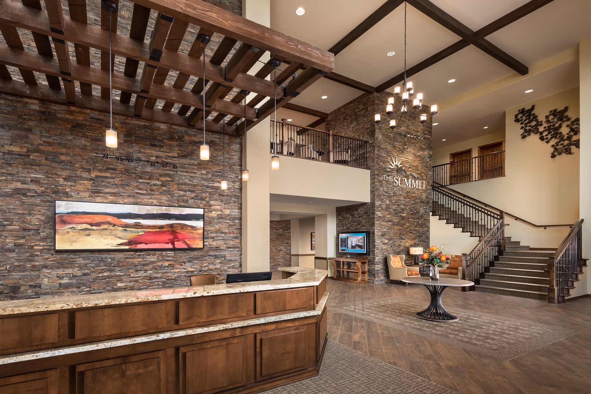 Spacious senior living lobby with stone accent wall, reception desk, staircase, and seating area.