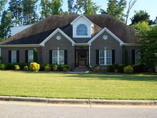 Front view of a brick senior living facility with a manicured lawn and shrubs.