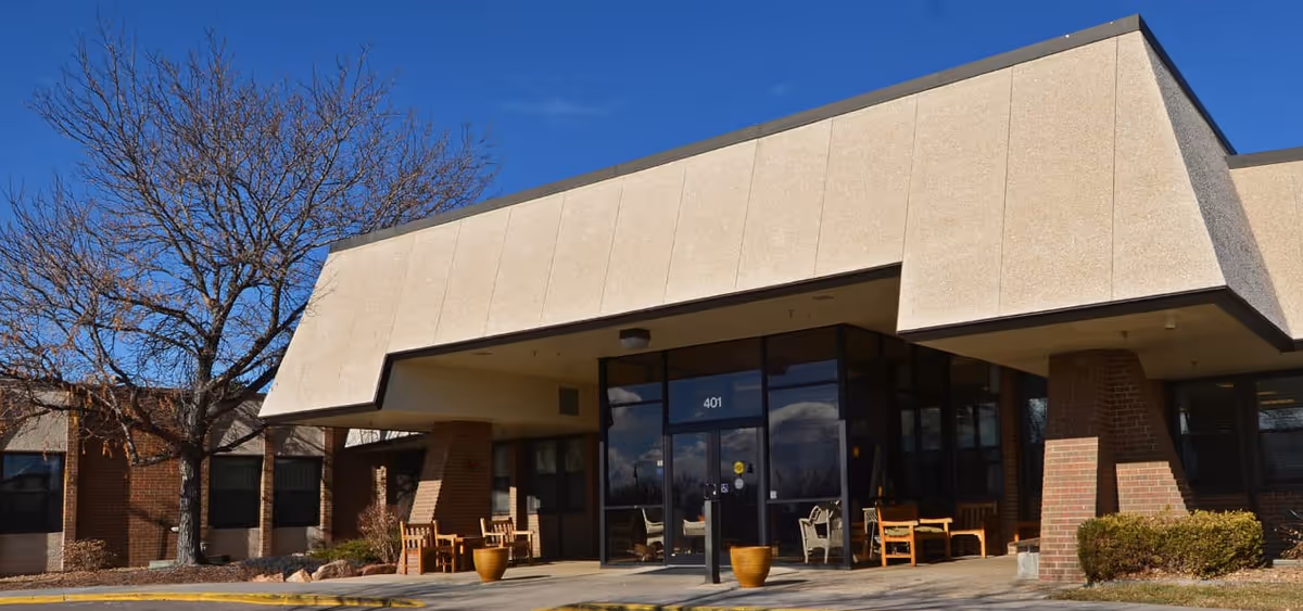 Exterior view of Avamere Transitional Care entrance with glass doors and outdoor seating.