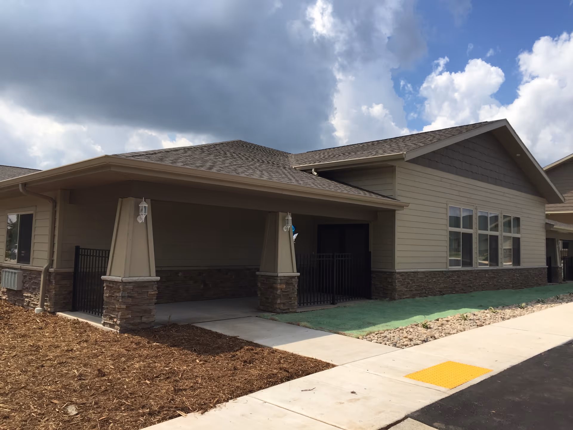 Single-story senior living facility with a covered entry, stone accents, and large windows.