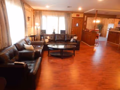Spacious lounge with leather sofas, wood floors, and a central circular coffee table.