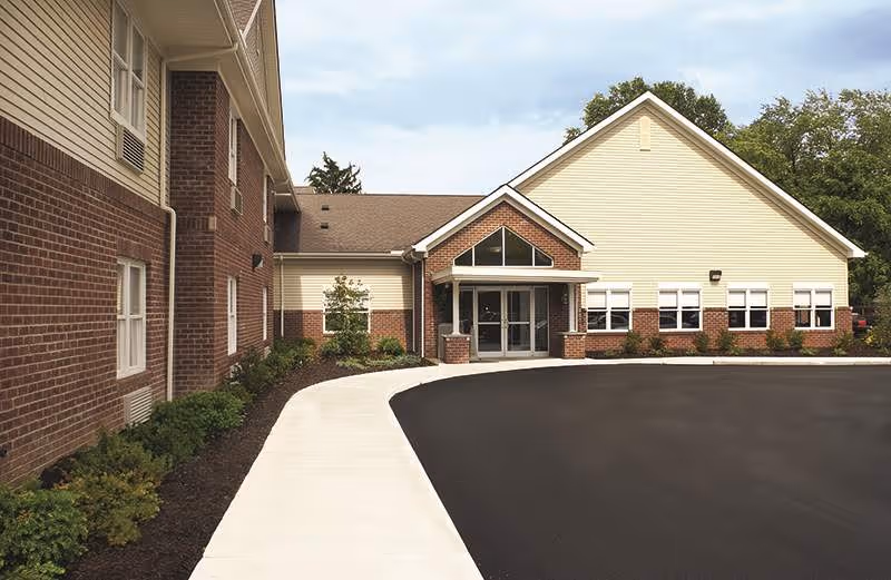 Front exterior of a brick and beige senior living facility with entrance.