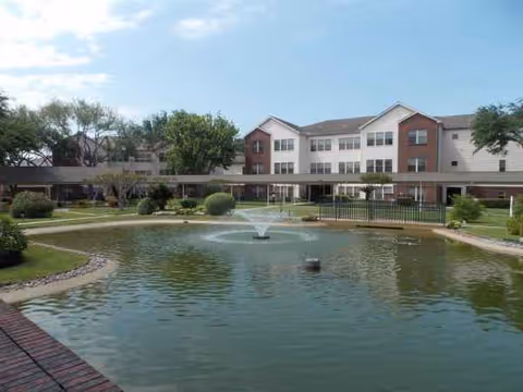 Front view of Lone Star Living facility with a fountain pond and landscaped courtyard.